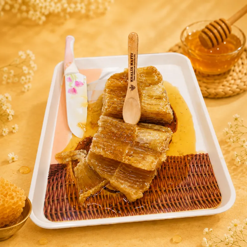 Sliced multiflora honeycomb served on plate with knife and pure honey jar, khalis hatti raw honey comb